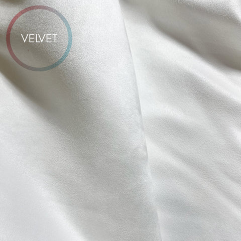 a close-up view of a white fabric, possibly velvet, with a circular logo containing the word "VELVET" in the top left corner.