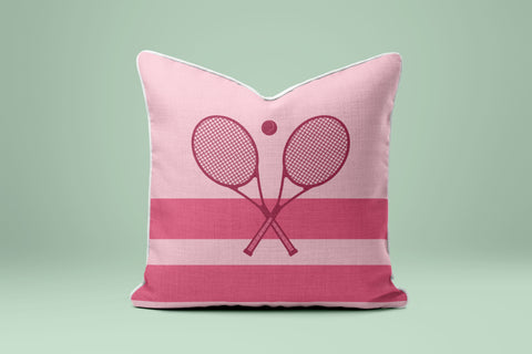 A pink and white striped pillow with a graphic of two crossed tennis rackets.