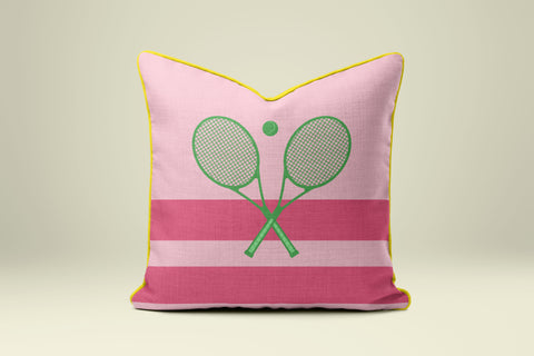 A pink and yellow throw pillow with a graphic of two crossed tennis rackets.