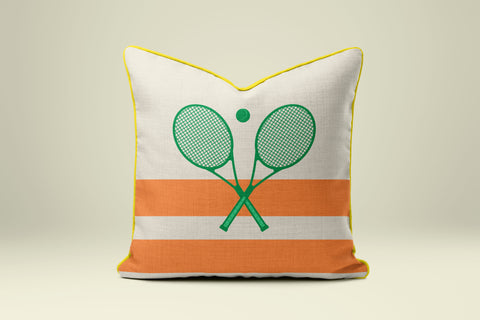A white and orange throw pillow with a graphic of two crossed tennis rackets.