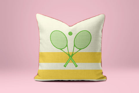 A white and yellow pillow with a graphic of two crossed tennis rackets on a pink background.