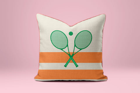 A white and orange pillow with a graphic of two crossed tennis rackets on it.