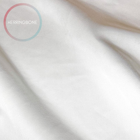 The image is a close-up of a white fabric with a herringbone pattern, featuring a circular logo with the text "HERRINGBONE" in the top left corner.